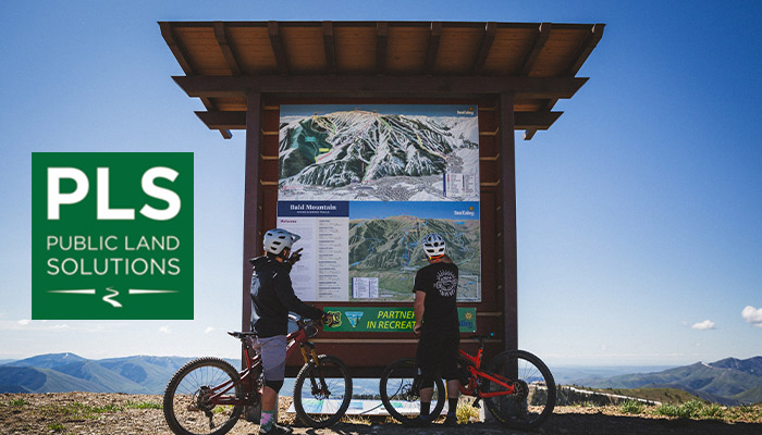 Riders at a trailhead sign.